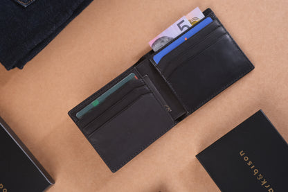 Open black wallet with banknotes and multiple cards visible on a brown surface with bark&bison branding.