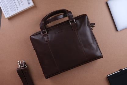 A dark brown leather handbag with detachable shoulder strap against a brown background.