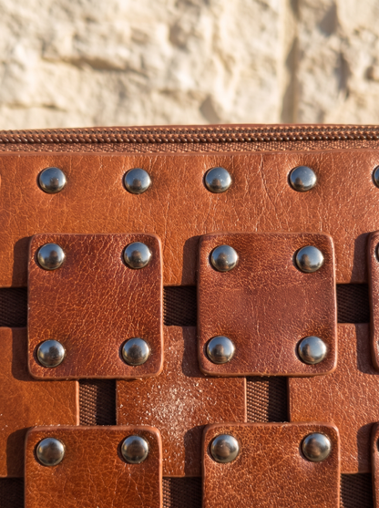 Macro detail of the Gawler Sling's woven leather panel and silver dome stud hardware