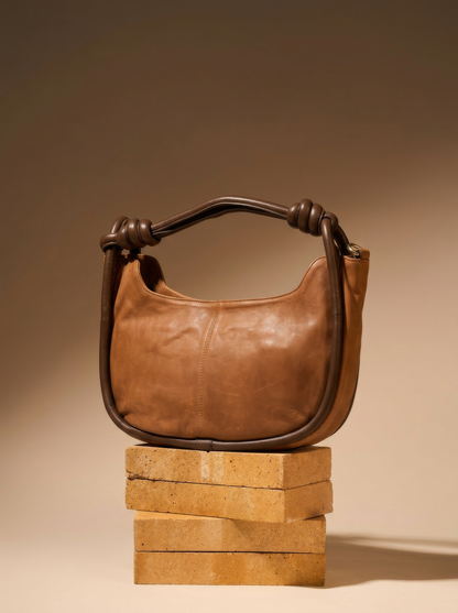 Pilbara Crescent tan leather hobo bag with knotted handle on a timber plinth, studio shot