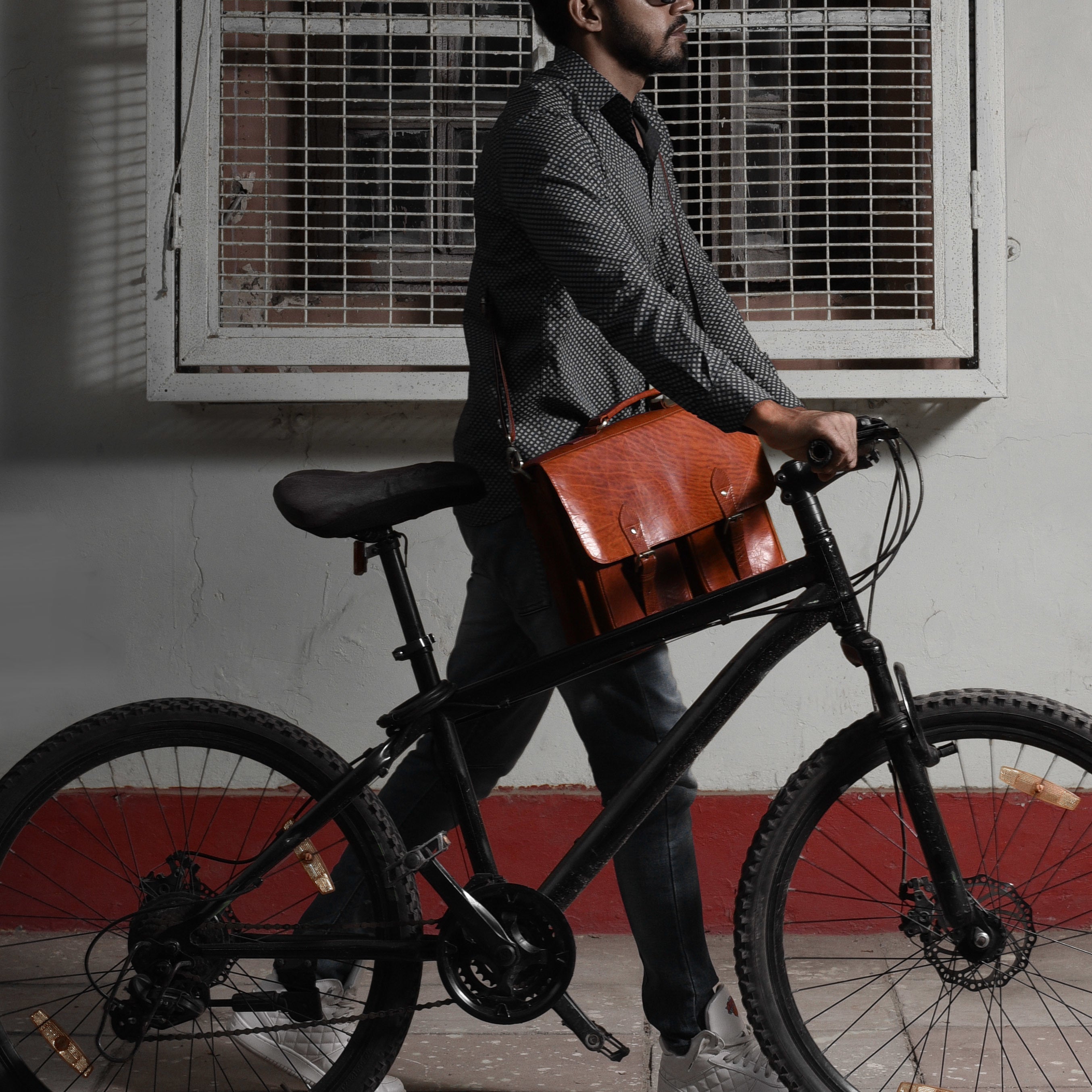 man biking with brown leather shoulder bag